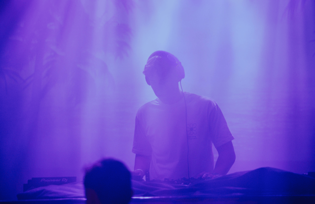 Flouze draait een house dj-set onder paarse lichten tijdens een live optreden vol elektronische energie