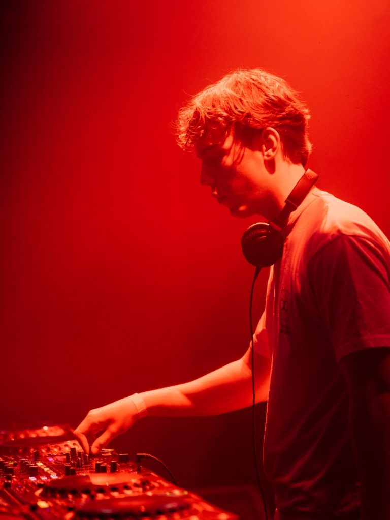 Flouze geeft een intense dj-performance met housemuziek tijdens een live optreden in een rood verlichte clubsetting